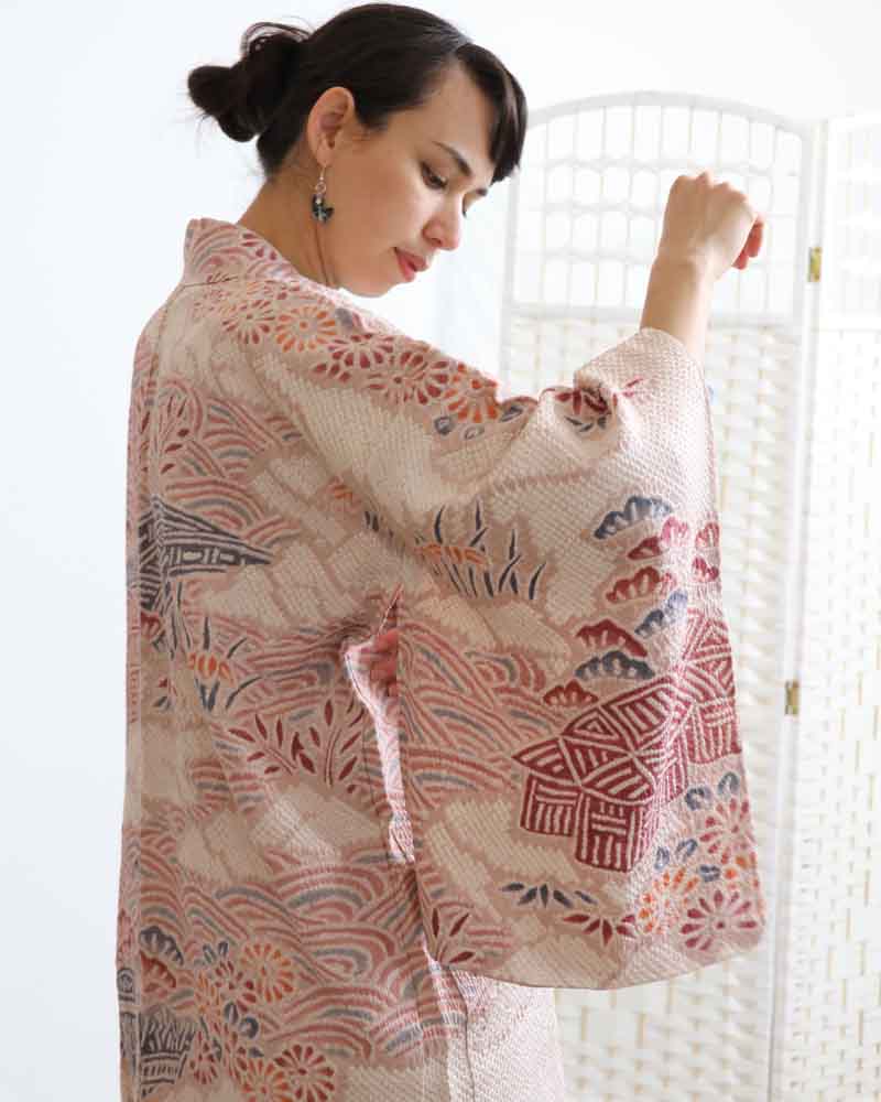 A woman wearing a pink kimono, facing side front.