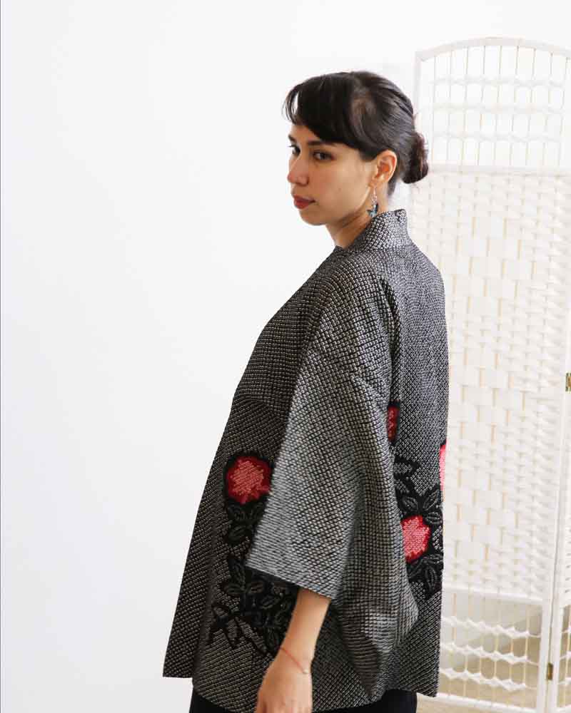 A woman wearing a black kimono, facing side front.