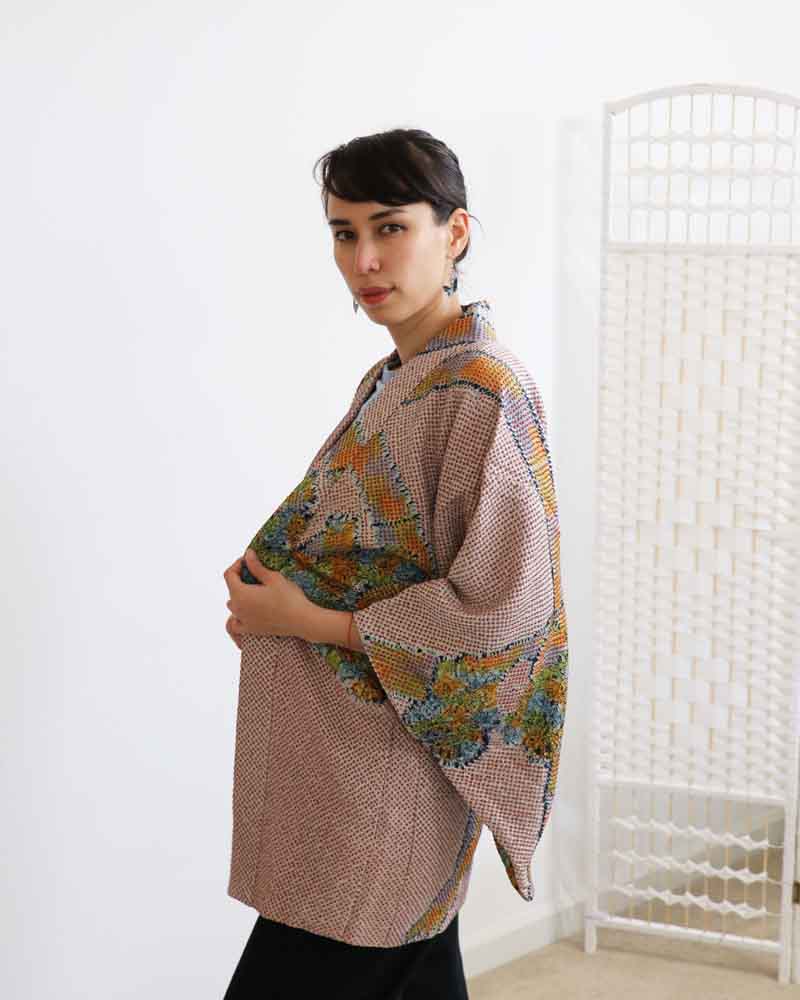 A woman wearing a  multi colors kimono, facing side front