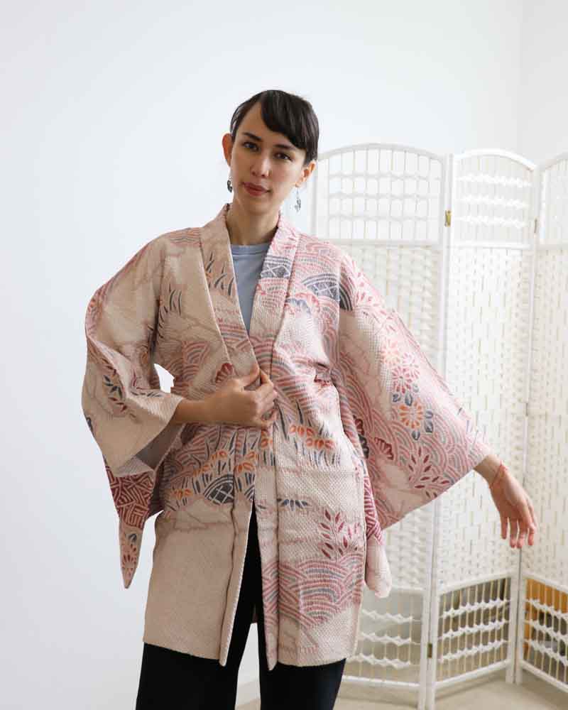 A woman wearing a pink  kimono, facing forward.