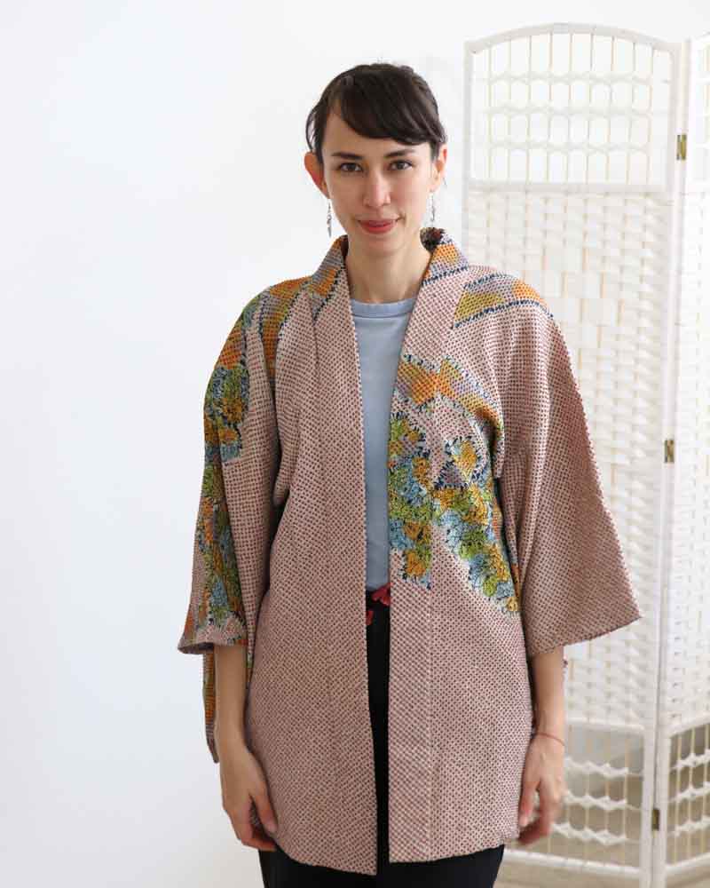 A woman wearing a multi colors kimono, facing forward.