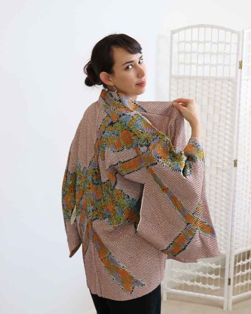 A woman wearing a  multi colors kimono, facing side front