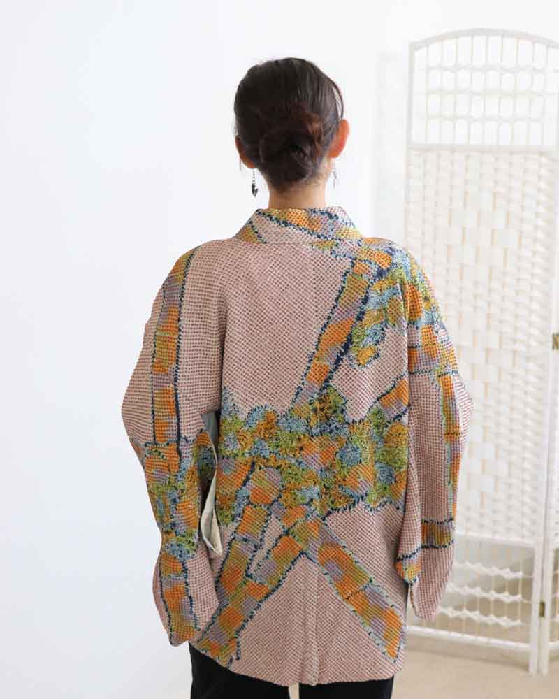 A woman wearing a multi colors kimono, facing backwards.