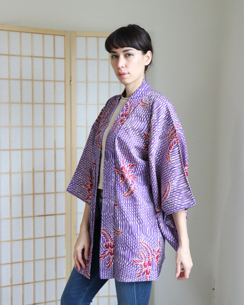 Front upper half of a woman wearing a Haori Kimono Jacket from the KIMONO ZEN brand in shades of Purple, white and red wisteria patterns