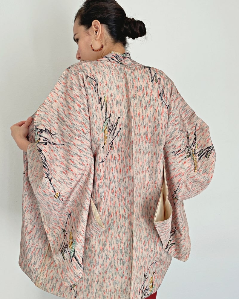 Upper back view of a woman wearing a KIMONO Zen brand Abstract painting Haori Kimono Jacket in a light pink shade.