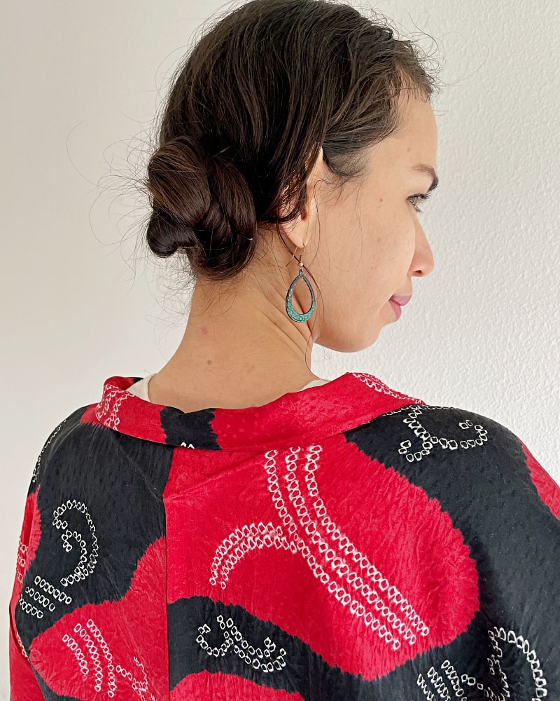 The Haori Kimono Jacket of the KIMONO ZEN brand, in shades of black and red, is shown from the back of the neck to the upper body of the woman wearing the jacket.