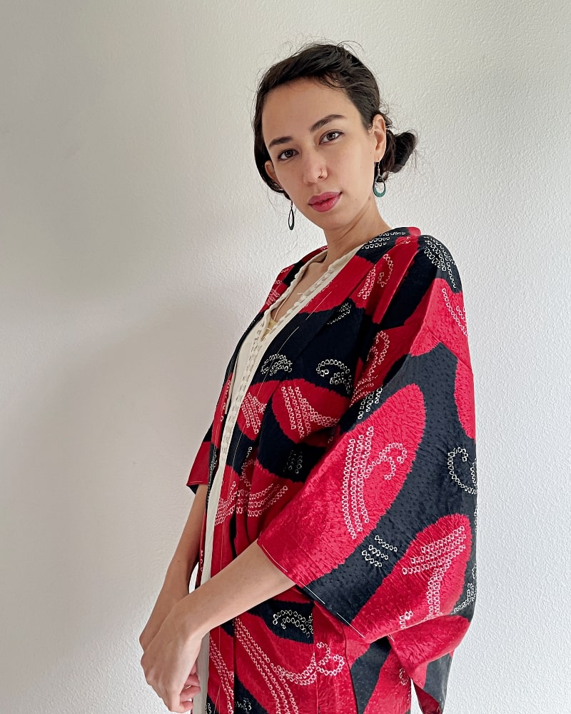 Haori Kimono Jacket of the KIMONO ZEN brand in shades of black and red, diagonally across the woman wearing the jacket, upper half of her body.