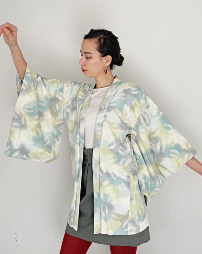 A woman wearing a KIMONO ZEN brand Aqua green ombre Haori Kimono Jacket, white with a light blue and gray pattern, seen from the side at an angle.