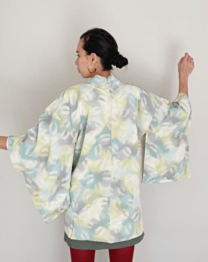 A woman wearing a KIMONO ZEN brand Aqua green ombre Haori Kimono Jacket, white with a light blue and gray pattern, seen from behind.