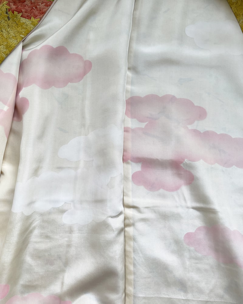 Autumn Leaves Forest Haori Kimono Jacket from the KIMONO ZEN brand, with a yellow/green mix of colors and autumn color lettering throughout, lined in white silk with pink clouds.