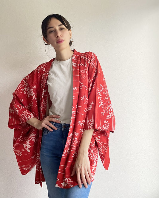 A woman wearing a KIMONO ZEN brand Bamboo Forest Haori Kimono Jacket in a shade of red with jeans and a white T-shirt.