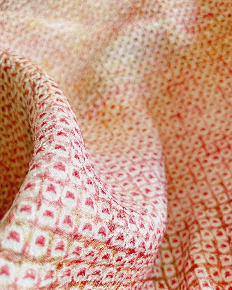 Enlarged photo of a pinkish shibori fabric with a plum tree pattern on it.