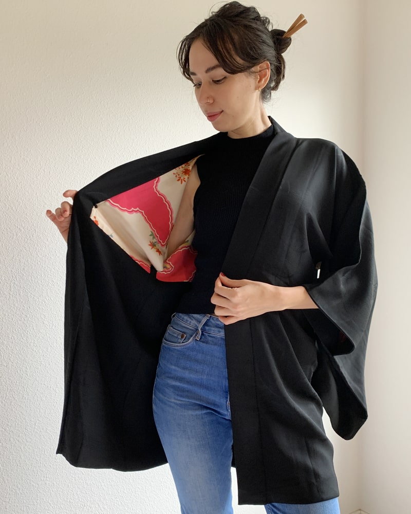Kimono zen brand Black with Aurora Glitter Thread Haori Kimono Jacket, black with red patterned lining, worn with a black cut and jeans.