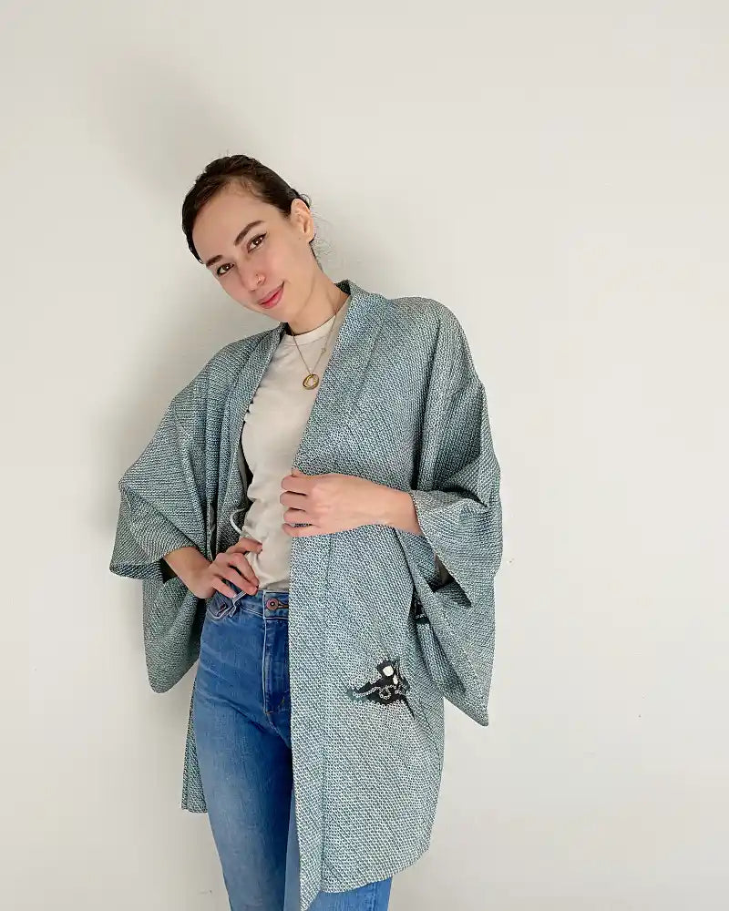 Woman wearing light blue butterfly-patterned kimono haori jacket with white T-shirt and jeans