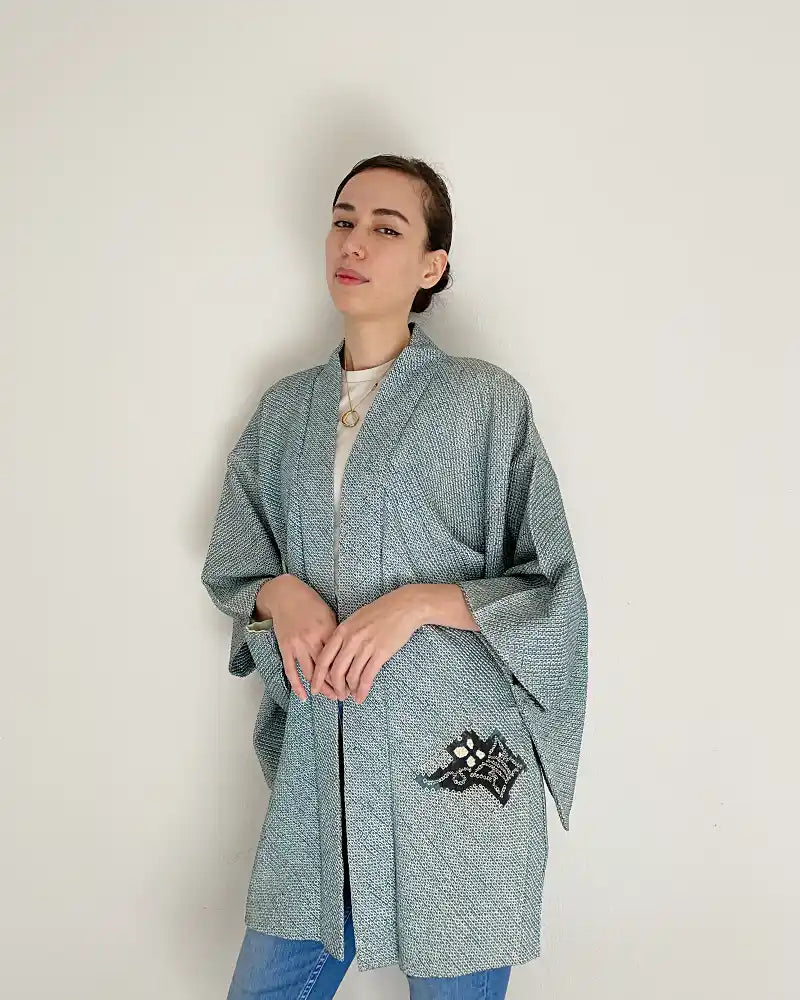 Woman wearing light blue butterfly-patterned kimono haori jacket with white T-shirt and jeans