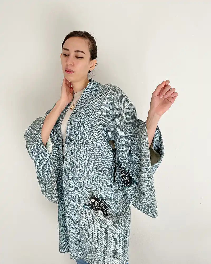 Woman wearing light blue butterfly-patterned kimono haori jacket with white T-shirt and jeans