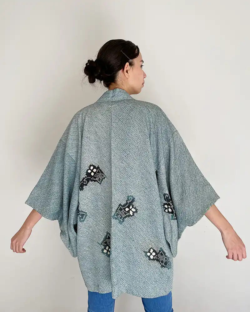 Woman wearing light blue butterfly-patterned kimono haori jacket with white T-shirt and jeans