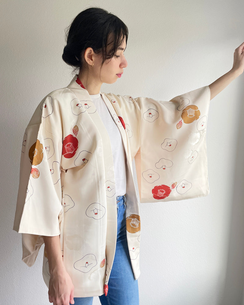 Woman wearing kimono haori jacket with red and golden camellia pattern on white fabric with white T-shirt and jeans