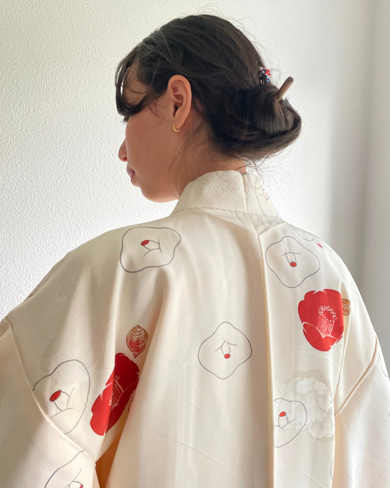 Woman wearing kimono haori jacket with red and golden camellia pattern on white fabric with white T-shirt and jeans