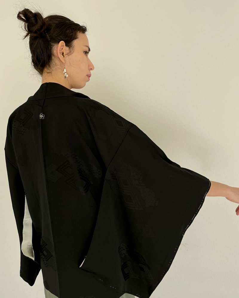 Black Rhombic Haori Kimono Jacket of Kimono zen brand, black fabric, back view of a woman wearing a green dress with it.