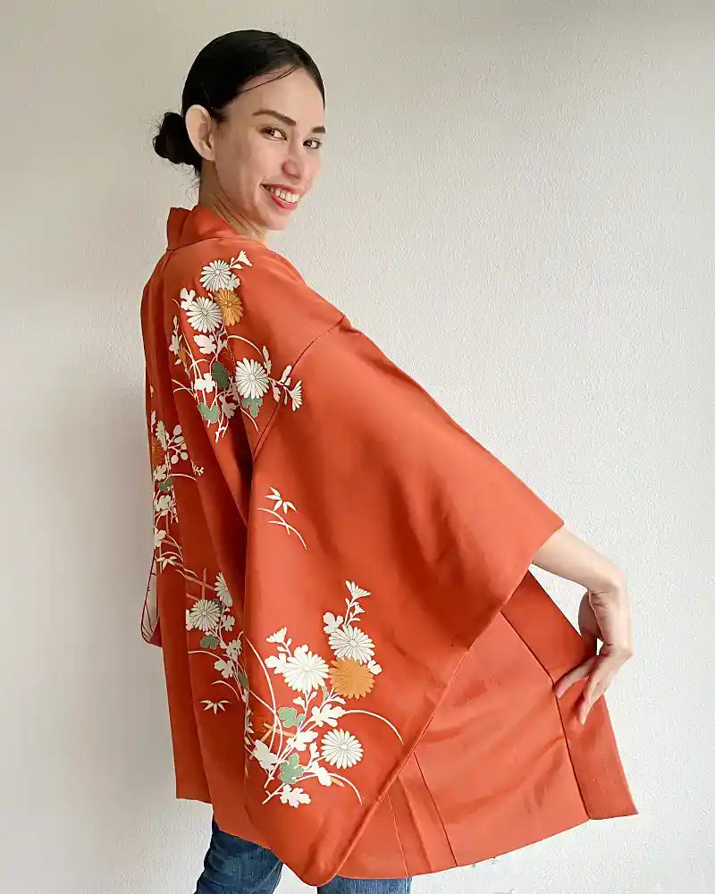 Woman smiling waering orange kimono jacket.