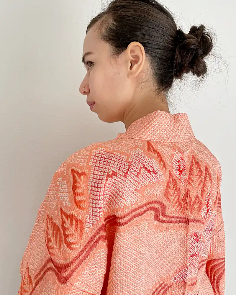 Colose up of woman wearing coral colored Shibori Haori jacket.